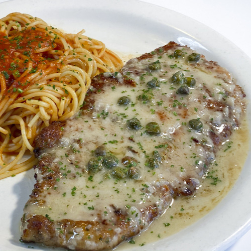Chicken Milanese Italian dinner -  Lightly breaded and pan-fried chicken breast topped with lemon butter sauce and capers. Served with spaghetti pomodoro.